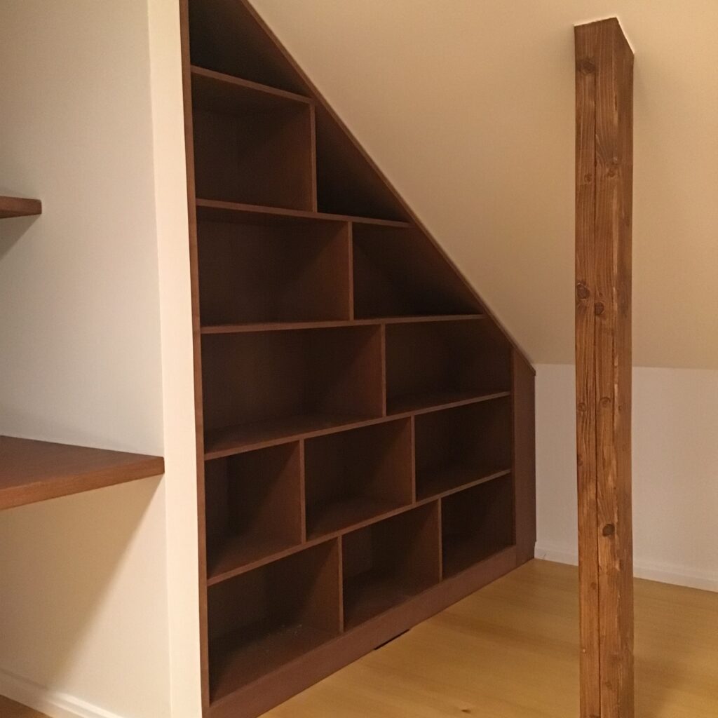 Hyllystö rakennettu vinokattoisen seinän päätyyn mittatilauksena.